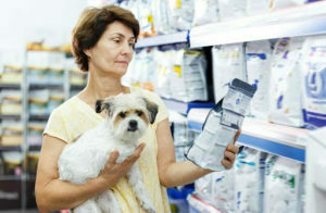 female dog owner with dog reading dog food packaging & it's label