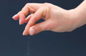 human hand releasing pinch of salt